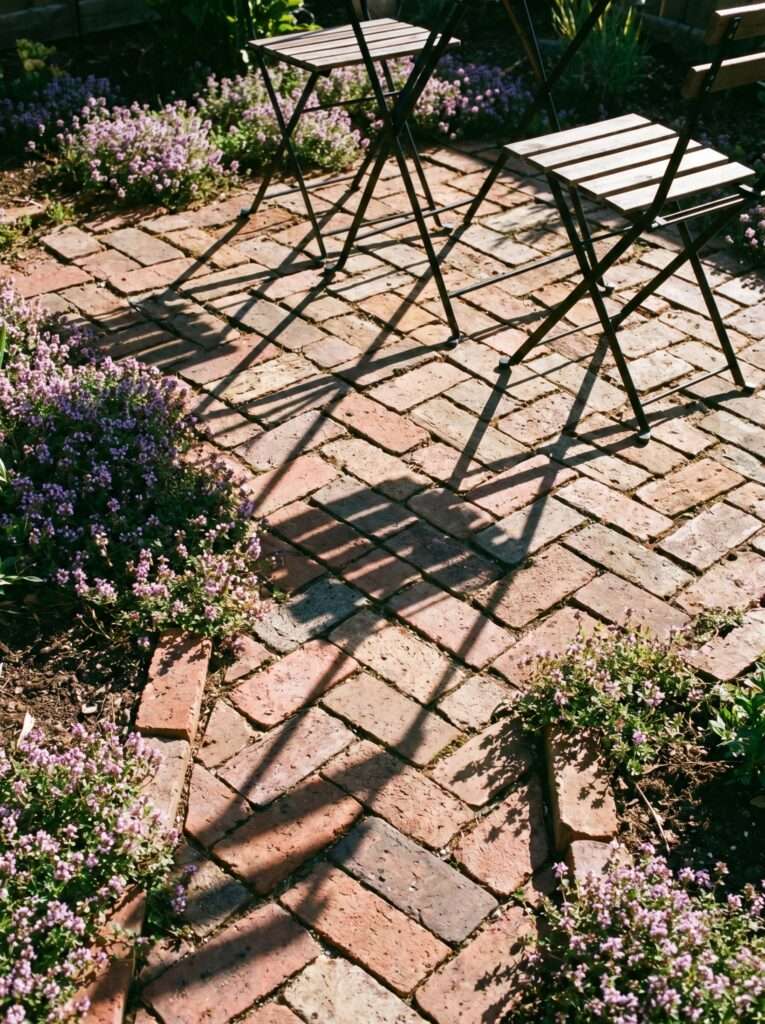 DIY herringbone brick paver seating pad with black iron folding bistro chairs.