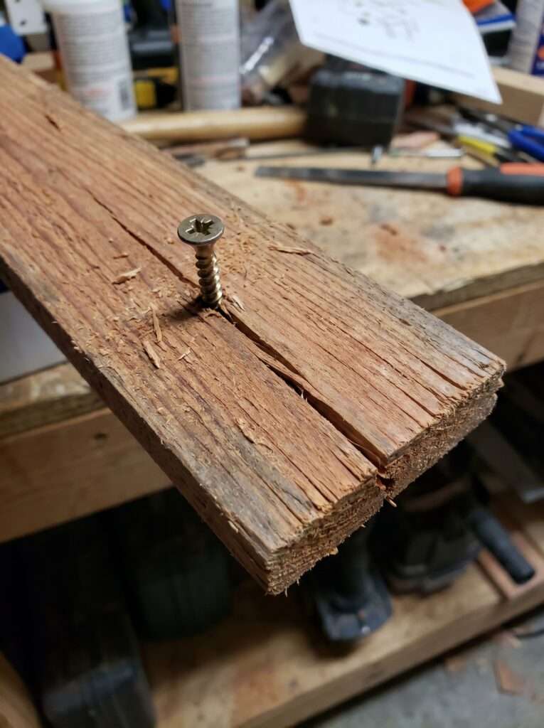 A split wooden board caused by failing to pre-drill a pilot hole for an exterior screw.