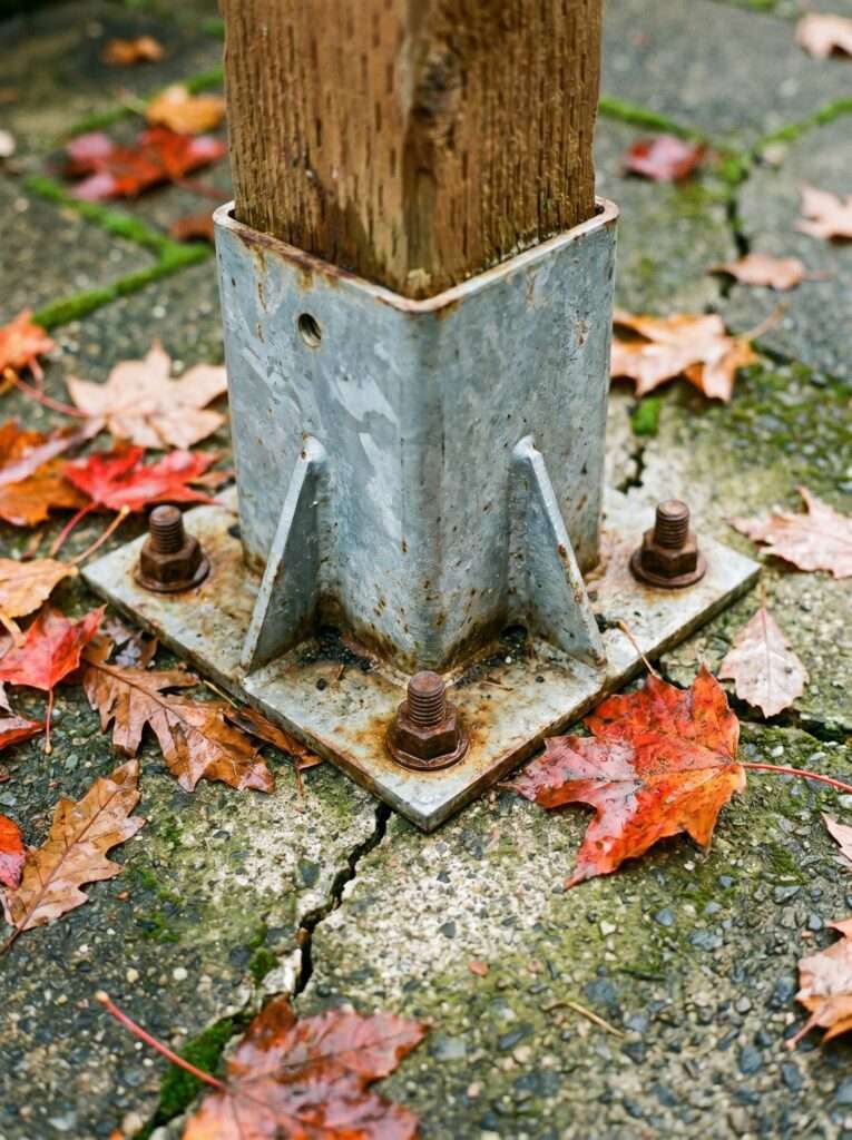 Heavy duty steel post base anchored into a concrete patio for a DIY privacy screen structure.