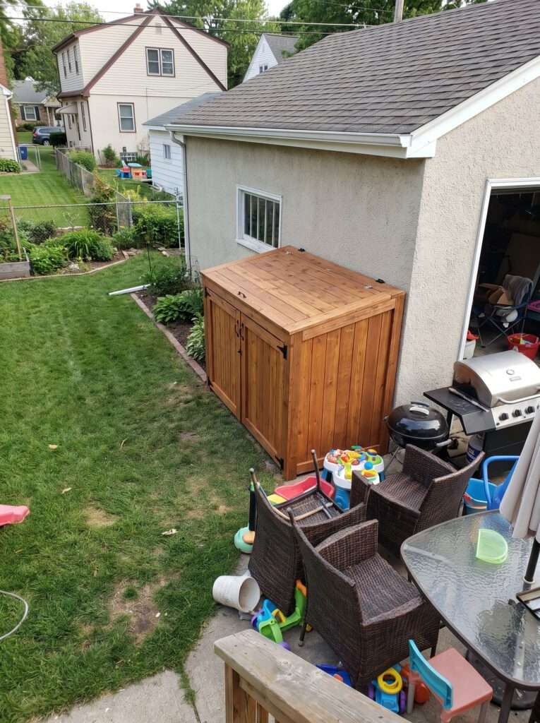  Finished DIY wood trash can enclosure next to garage in suburban yard