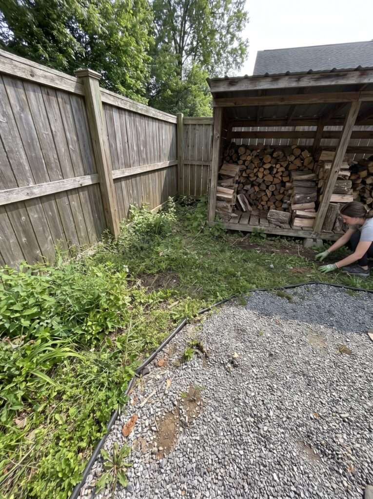  firewood shed positioned near fence and gravel garden path in backyard