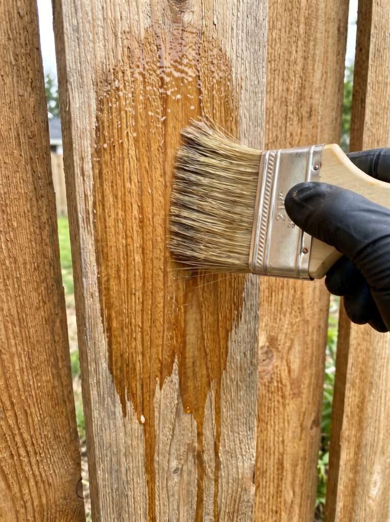 Applying exterior wood sealant to a DIY trash can enclosure panel 