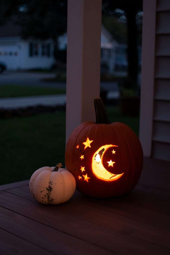 Moon and star carved pumpkin glowing on front porch