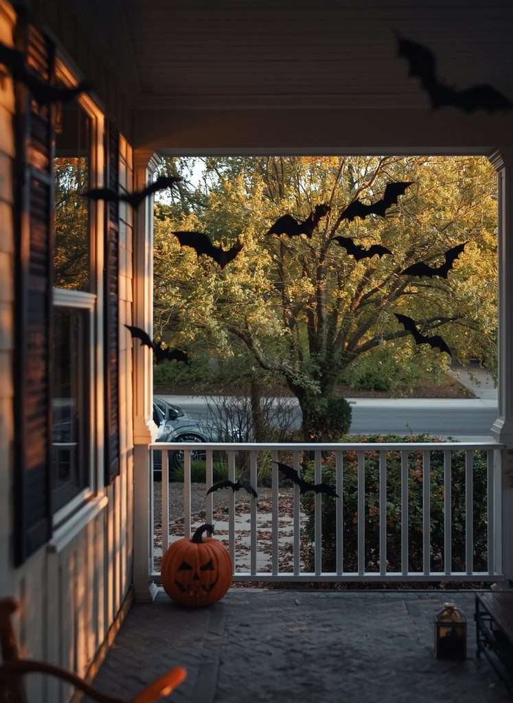 Black bat decorations flying around a spooky Halloween porch.