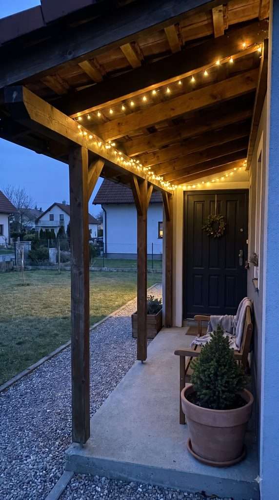 Warm white Christmas string lights attached along the ceiling beams of a covered front porch.