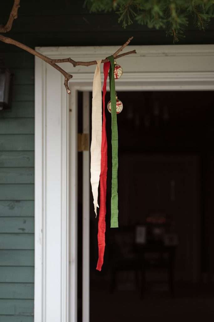 Decorated natural branch with ribbons and ornaments above doorway