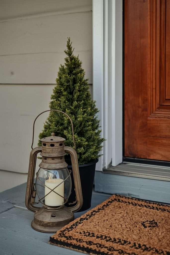 Vintage-style lantern beside an evergreen Christmas porch planter.