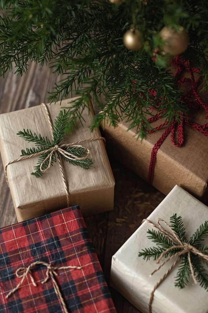 Kraft paper Christmas gifts decorated with plaid ribbon and evergreen sprigs.