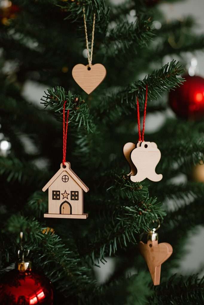Handmade wooden stars and houses hanging on a traditional Christmas tree.